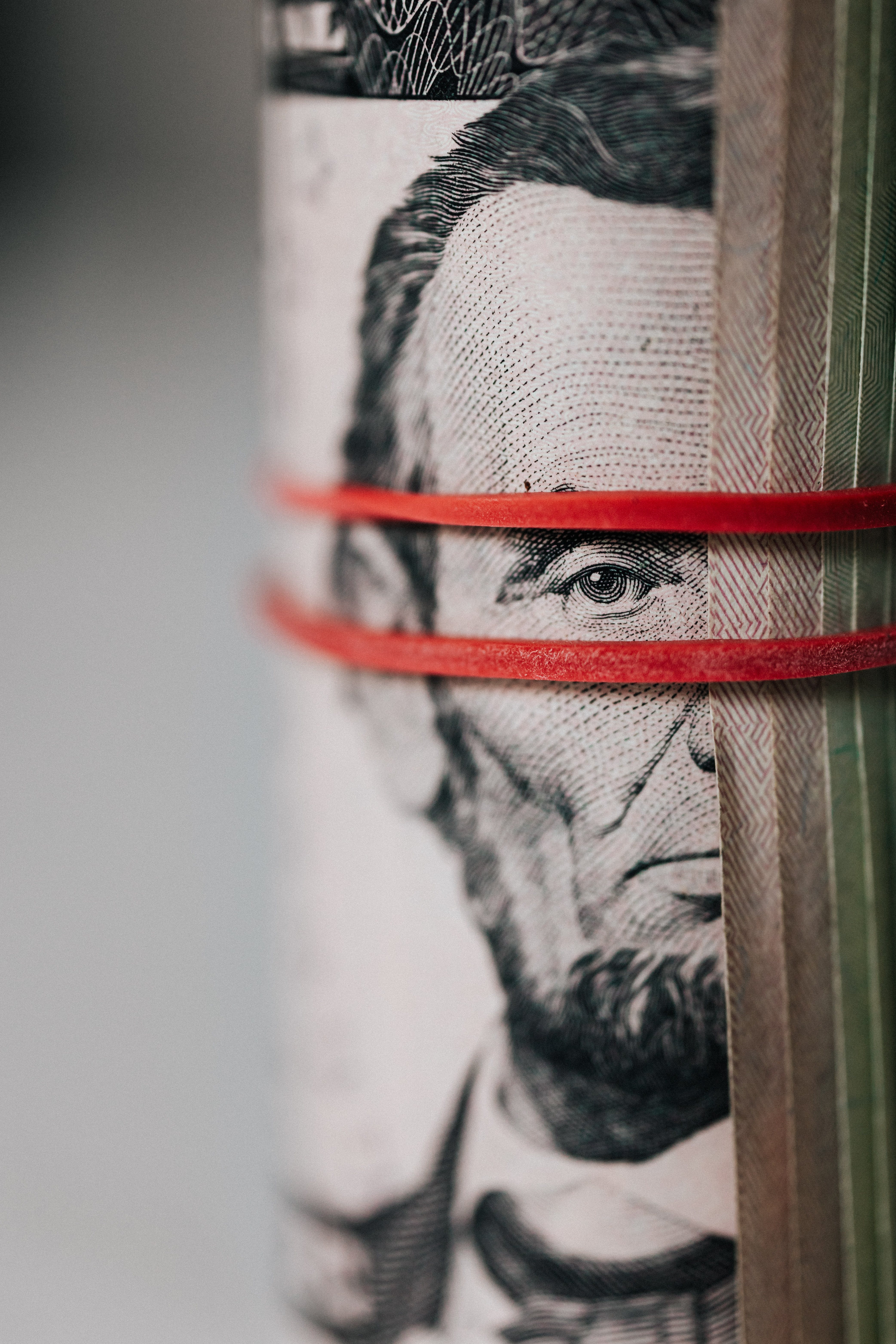 Free Closeup of rolled United States five dollar bills tightened with red rubber band Stock Photo